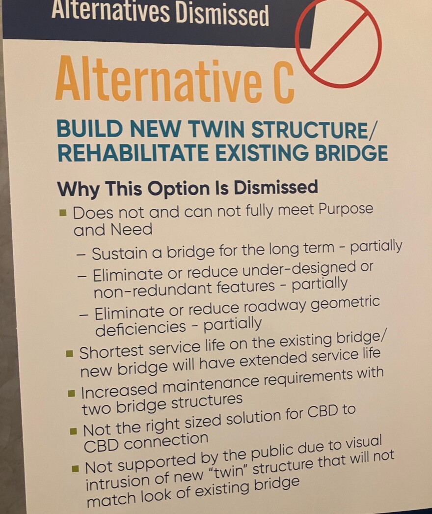 A placard listing reasons why building a twin structure next to the existing bridge, and rehabbing the current bridge was dismissed.