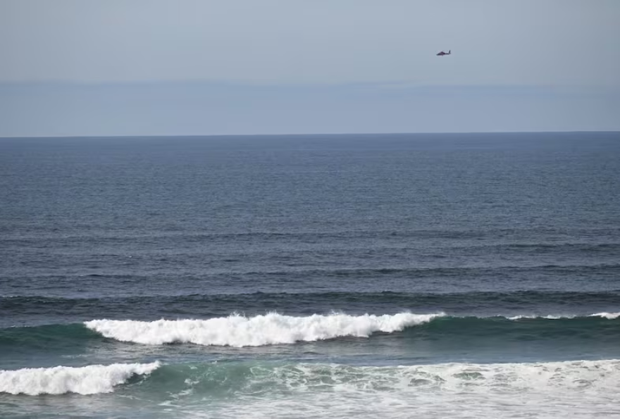 A U.S. Coast Guard helicopter searches the ocean just west of downtown Newport for a twin-engine plane that crashed into the water about 12:45 p.m. Monday.