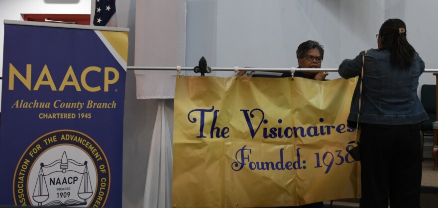 Members of the Alachua County NAACP and Visionaires Inc. help set up before the meeting begins. (Harrison Leveton/WUFT News)