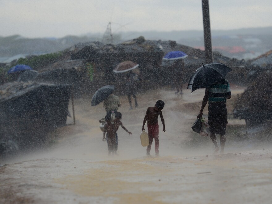 A Rohingya child carries water through a rainstorm at a refugee camp in October 2017.