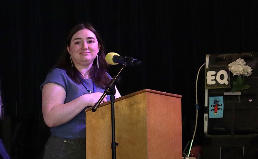 Person stands at a podium on a stage.