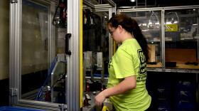 A worker at a factory in North Vernon, Indiana, works with a plastics manufacturing robot.
