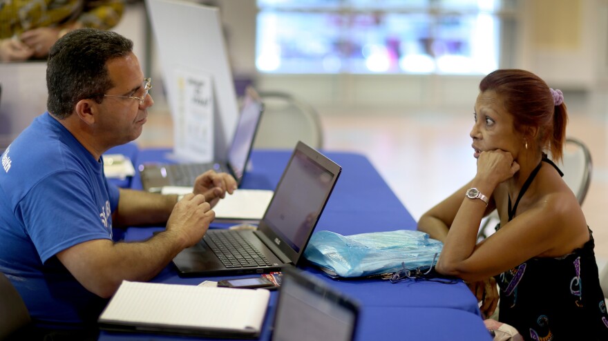 Mario Ricart , an insurance agent with Sunshine Life and Health Advisors, talks with Naylie Villa about buying insurance under the Affordable Care Act on Nov. 5 in Miami.