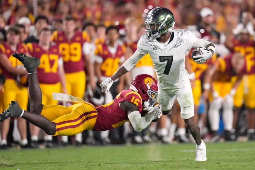 Oregon wide receiver Evan Stewart is shown on his feet breaking a tackle by a USC player.