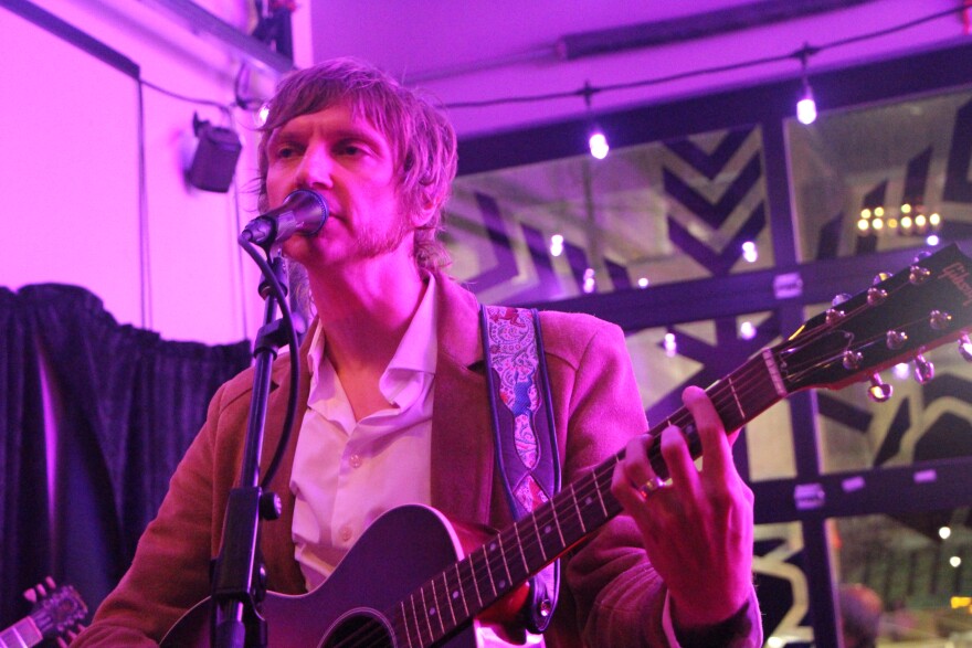 Man playing guitar and singing into a microphone