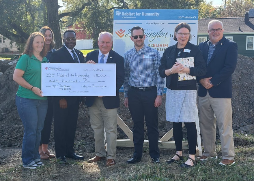 seven people stand behind a large check 