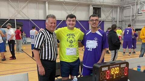A Special Olympics coach and an athlete pose for a photo with a referee at the Special Olympics basketball tournament at Niagara University in May 2025.