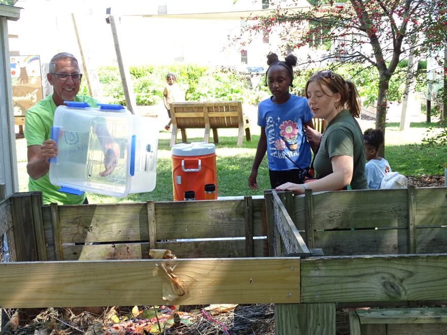 Rick Roszkowski empties food scraps the campers delivered into the garden's composting system.