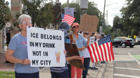 Valerie Fuldauer, 76, holds a sign with the words “ICE belongs in my drink not in my city.” (María Sofía Rodríguez/WUFT News)