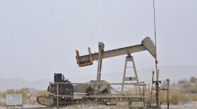 An oil well pumps during a snowstorm in the checkerboard region of northwest New Mexico.