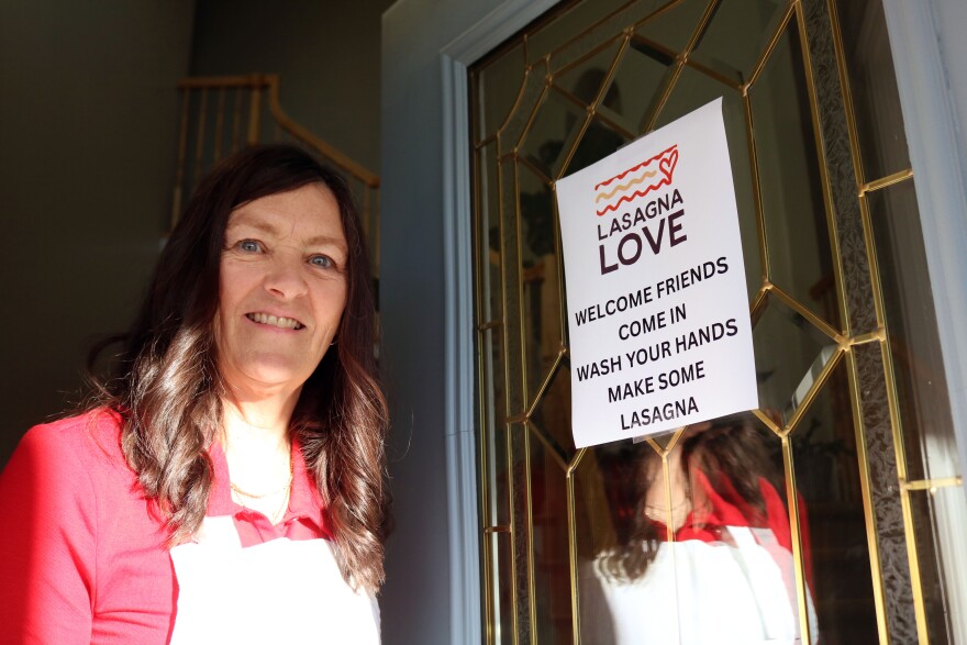 Lori McDougal stands next to a sign on her front door that welcomed guests to her lasagna party, Nov. 13, 2025