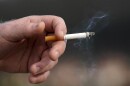 FILE - A man holds a lit cigarette while smoking in San Francisco.