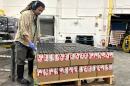 A Nine Pins Ciderworks employee with cases of the company's product. For its cans, the North Albany business needs aluminum sheets imported from Canada. That aluminum is now subject to steep tariffs, raising the company's canning costs.