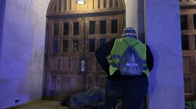 A volunteer participating in the Point-in-Time Count surveys a person sleeping outside First United Methodist Church in Uptown.