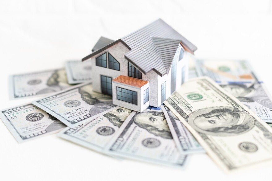 a house sits on hundred dollar bills 