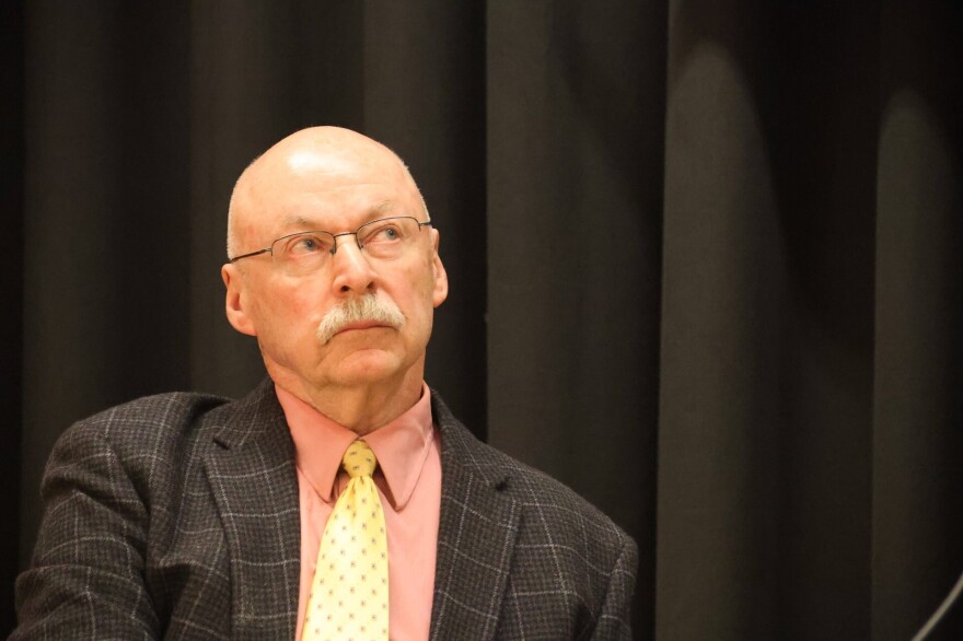 A man in a suit, with a black background.