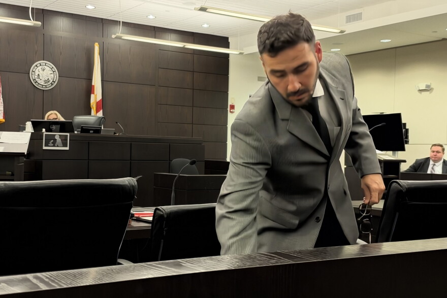 Luis Rodriguez, the Public Defender who is representing Ita Durand, in the courtroom placing his bags down where he will be seated.