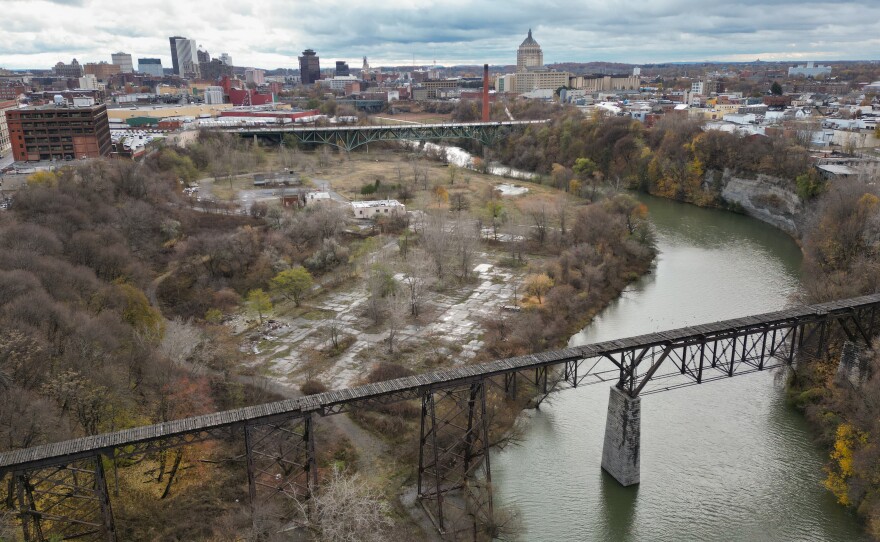 This aerial photo shows a river surrounded by green space and buildings.