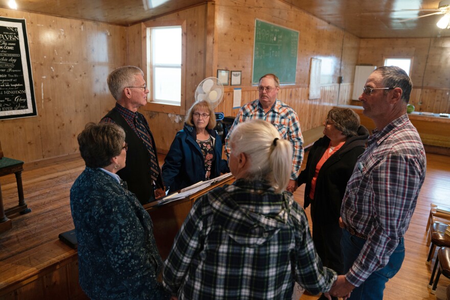 Ranchers gather with traveling pastor Hal DeBoer for a religious service at First Creek Community Hall.