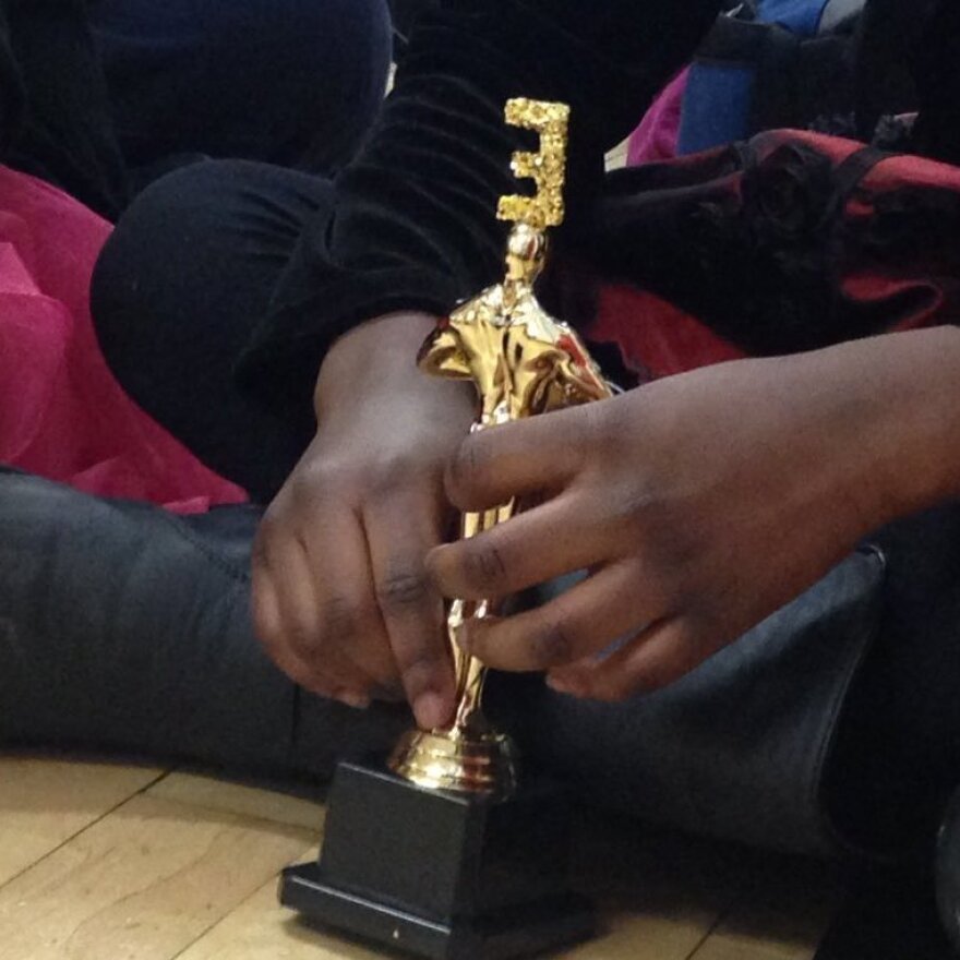 A student holds her Academy Award of Excellence statue.