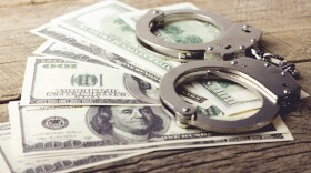 handcuffs sit atop half a dozen 100 dollar bills