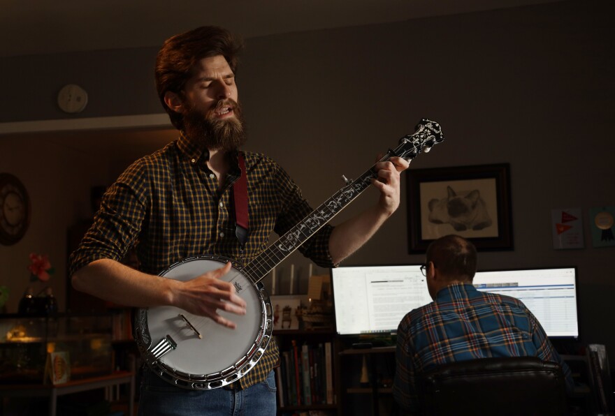 Philip Detrick plays the banjo as his brother works from home. Detrick moved into his brother's Webster home in September and hopes to get his own apartment soon.