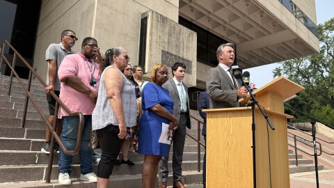 Following the filing of a lawsuit seeking a million dollars in damages, Attorney Jeffrey Morneau (right, at podium) announced details of the complaint