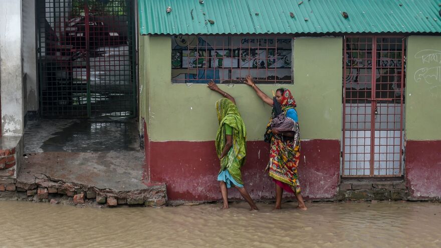 Residents gingerly tread a flooded street on their way to a shelter Wednesday in the border city of Khulna, Bangladesh.