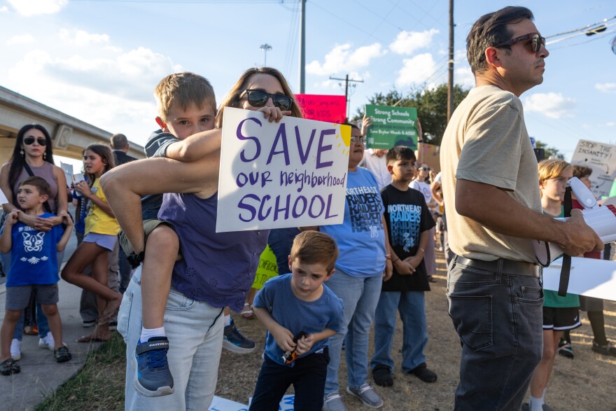 Kate Shwartz carries her son, Hugo, 6, on her back during a protest at Austin Independent School District building on Oct. 9.