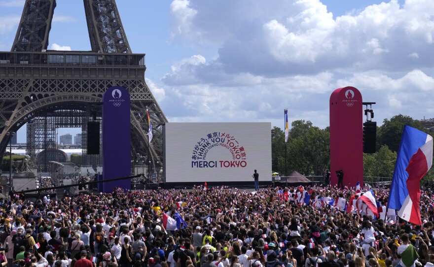 Spectators gather by the Eiffel Tower in Paris as part of the handover ceremony during the closing ceremony of the Tokyo Olympic games.