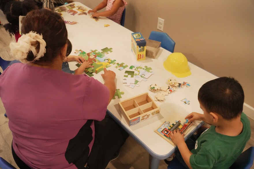 A teacher and kids working on a puzzle in an early education program. 