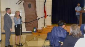 Keller ISD Superintendent Tracy Johnson takes the microphone during a Feb. 21, 2024, town hall meeting at Basswood Elementary. Fort Worth City Council Member Charles Lauersdorf stands to her right. Keller ISD parents and administrators are protesting the construction of a Studio 6 extended stay hotel. Dev Surati, the hotel's owner, stands in the background.