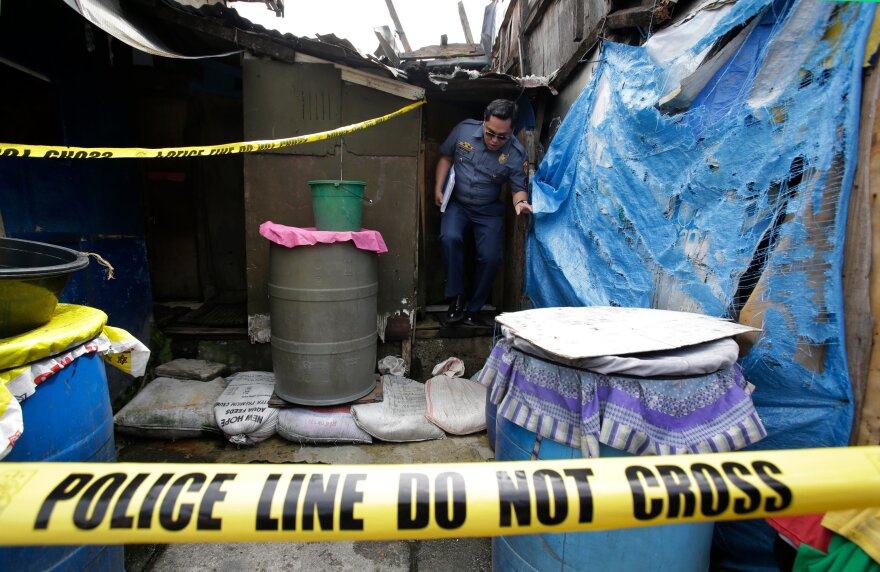 A policeman comes out of the shanty home of two brothers and an unidentified man who were killed during an operation as part of the continuing war on drugs in Manila, Philippines, Oct. 6, 2016.