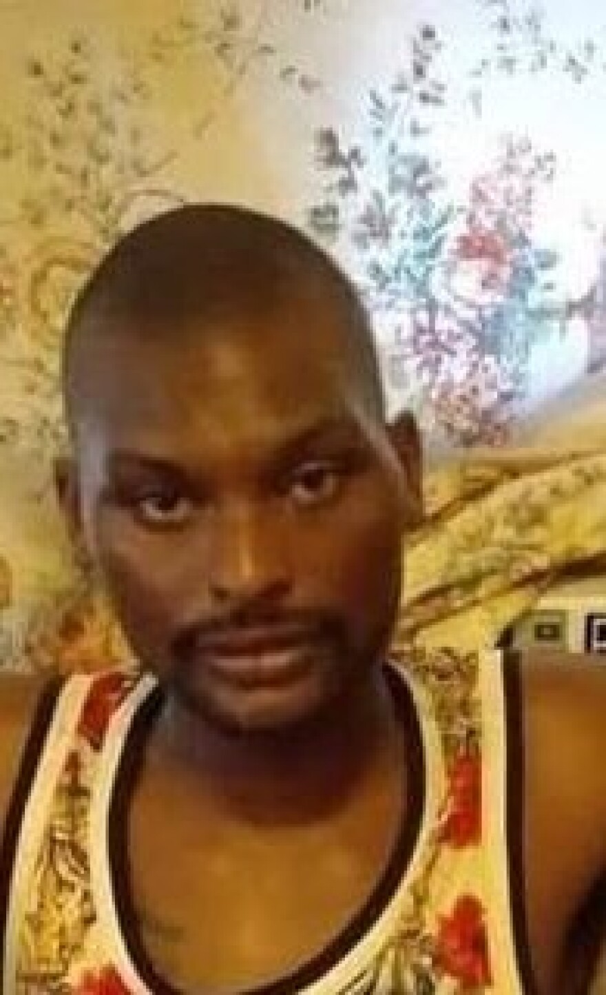 The image is of an African American man in front of a brown curtain. 