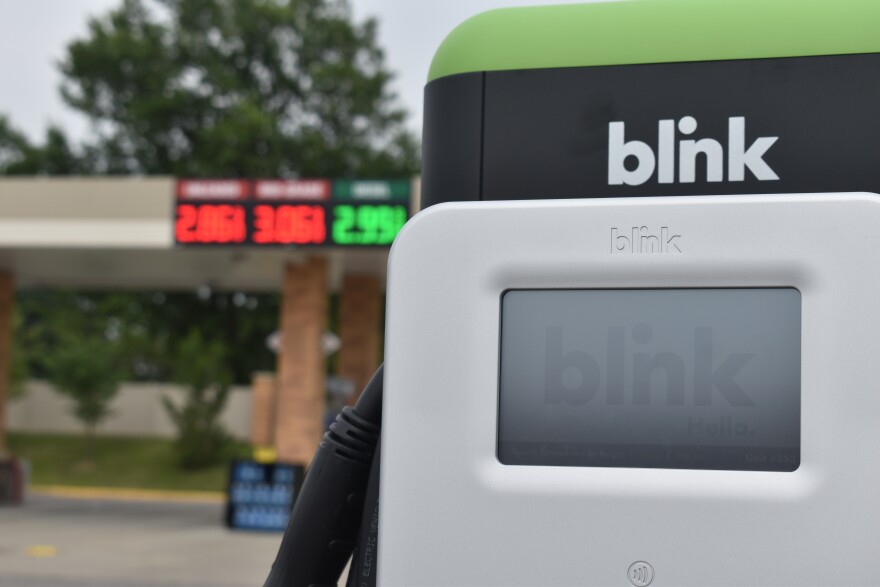 An electric vehicle charger sits in the foreground of a gas station in Columbia. Despite improvements to electric vehicles and infrastructure, some hurdles to EV adoption remain in Missouri — especially rural areas. 