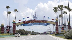 FILE - Cars drive under a sign greeting visitors near the entrance to Walt Disney World, July 2, 2020, in Lake Buena Vista, Fla. The first meeting of the new board of Walt Disney World’s government — overhauled by sweeping legislation signed by Republican Gov. Ron DeSantis as an apparent punishment for Disney publicly challenging Florida’s so-called “Don’t Say Gay” bill — dealt with the rote affairs any other municipal government handles. Board members on Wednesday, March 8, 2023, faced calls for better firefighter equipment, lessons on public records requests and bond ratings. (AP Photo/John Raoux, File)