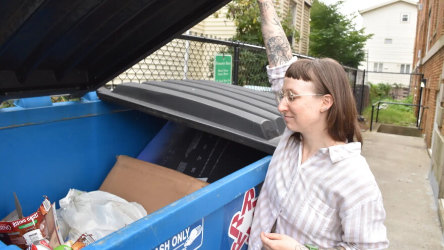 Grace Wexler shows off the trash dumpster full of recyclable material outside her Malden apartment building. The recycling bins were removed by the building's management company.
