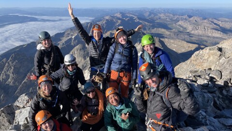 A group of women pose at the top of the Grand Teton with smiles all around.