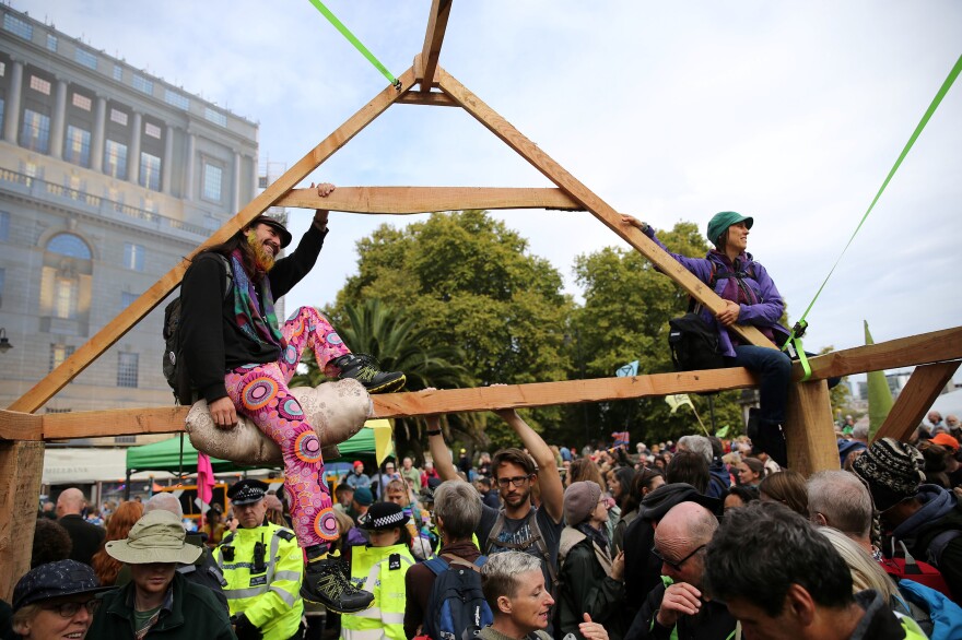 Extinction Rebellion activists sit atop a temporary wooden structure as they demonstrate on Lambeth Bridge on Monday.