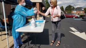 Nurse Michelle Laracy hands Watertown schools staff member Maureen Craig a swab for a coronavirus test outside Watertown Middle School. (Angus Chen for WBUR) 