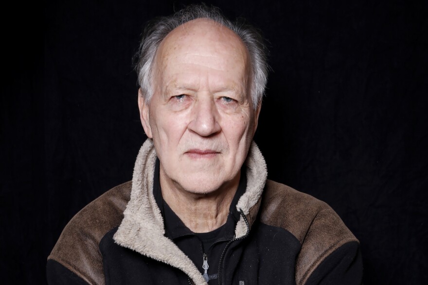 A man stares into the camera against a black background.