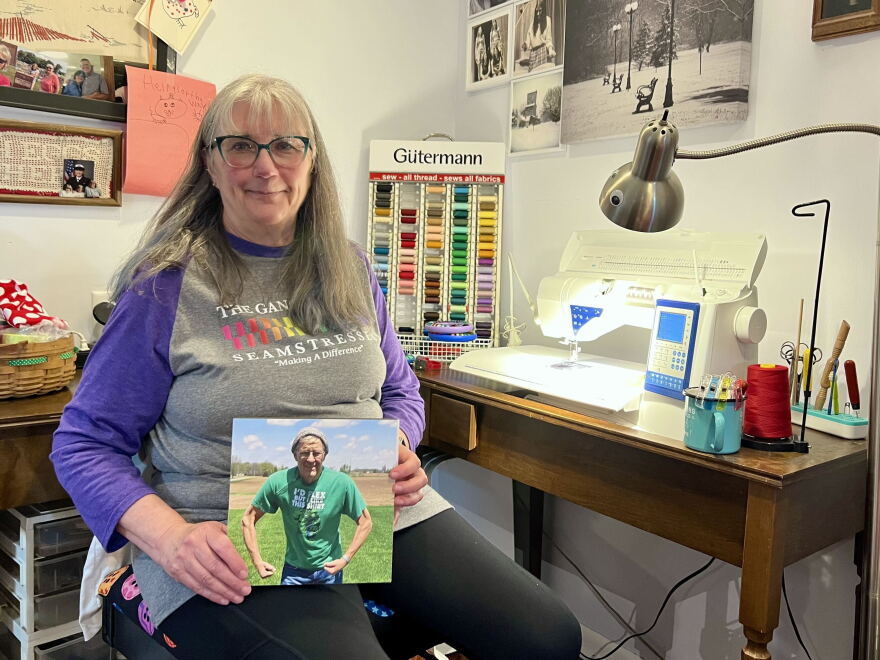 Pat Cochran holds up a photo of her late friend, Dennis Seger. She started the 'Gang of Seamstresses' to help him during his chemotherapy treatments.