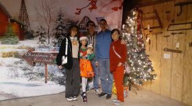 A family of five stands for a photo in front of a holiday tree. 