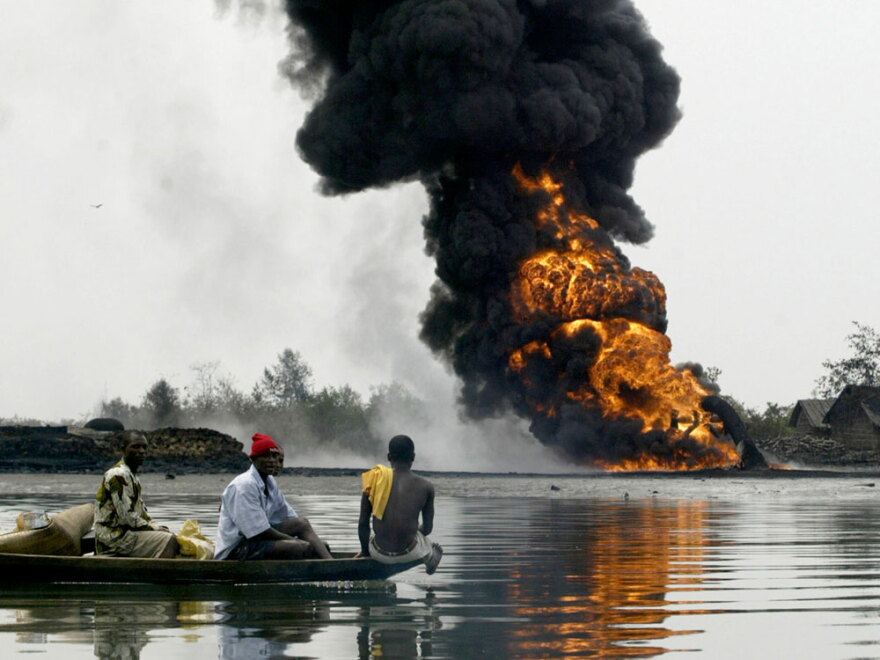 For decades, oil has spilled from pipelines and rigs in Nigeria's Niger Delta on a scale dwarfing the BP oil disaster that is fouling the Gulf of Mexico. In this 2005 file photo, people evacuate their homes by boat, passing smoke and flames billowing from a burning oil pipeline belonging to the Shell Petroleum Development Co.