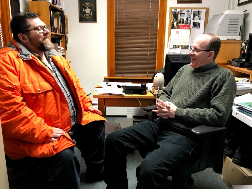 Patrick Warn talks in an office to Lamoille County Sheriff Roger Marcoux.