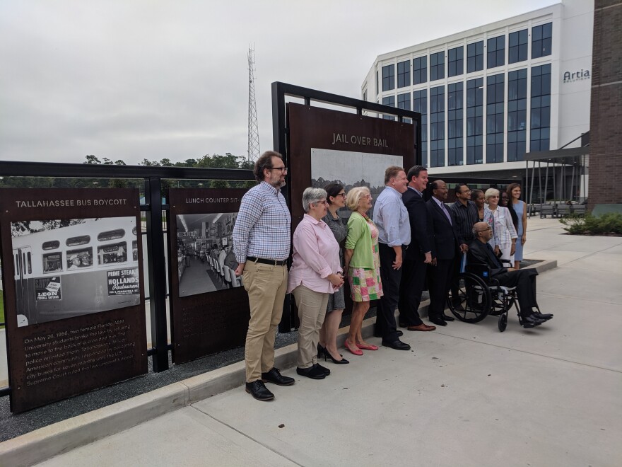 Several people pose for a picture standing in front of large photographs affixed to metal stands.