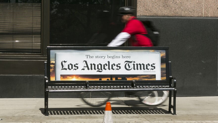 A cyclist rides on the sidewalk past the Los Angeles Times building in downtown Los Angeles. The paper's Saturday deliveries were affected by an interference with Tribune Publishing's print production systems.