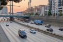Cars and trucks travel on a highway in the morning after sunrise.