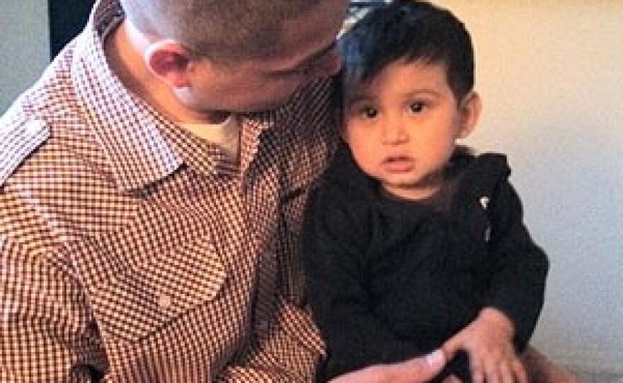 Alfonso Santos plays with his 1-year-old son Ezrah, as Ezrah's mother Kimberly Hernandez looks on from their kitchen in Caldwell, Idaho.