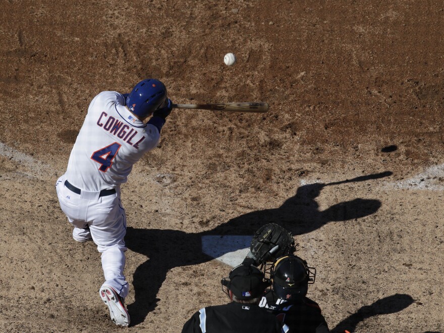 A photo taken through a safety net shows New York Mets' Collin Cowgill hitting a home run against the Miami Marlins at Citi Field, April 6, 2013 in New York.